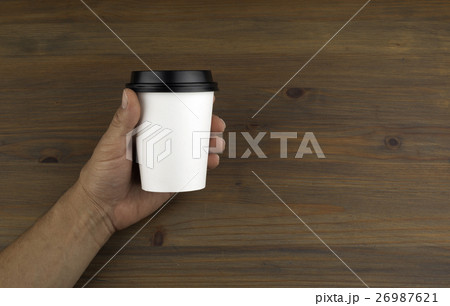 Paper cup of coffee in hand on wooden background Paper cup of coffee in hand on wooden background 26987621