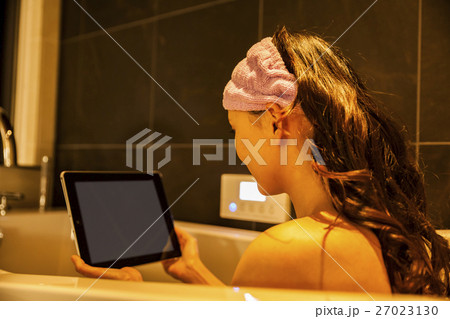 半身浴をしながらタブレットを見る女性 27023130