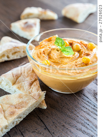 A bowl of hummus with pita slices 27026023