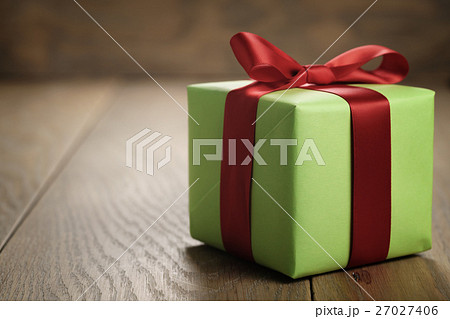 simple green paper gift box with red ribbon bow on oak table with copy space 27027406