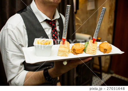 Waiter carries square dish with cake  Waiter carries square dish with cake  27031648