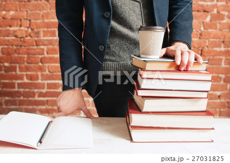 Student near stack of books and coffee-to-go cup 27031825