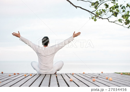 Man in white clothes meditating yoga on wooden Man in white clothes meditating yoga on wooden 27034456