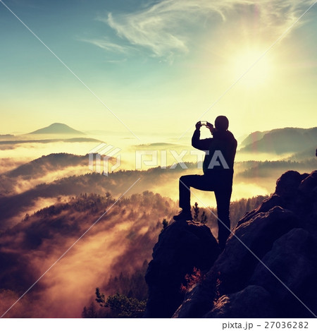 Hiker man photograph lovely misty valley from rock 27036282