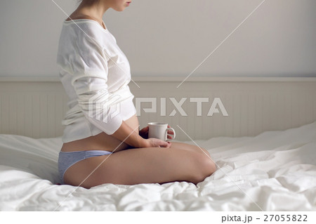 pregnant woman sitting in a white bed in t-shirt pregnant woman sitting in a white bed in t-shirt 27055822