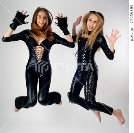 Two pretty girls in cat costumes jumping 27056399