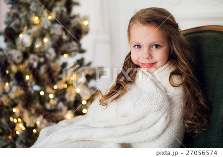 Cute little girl sits by the christmas tree 27056574