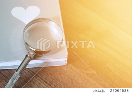 Magnifier over the book on wooden table 27064688