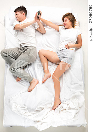 The young lovely couple lying in a bed with alarm 27066769