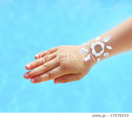 Hand of the baby with suntan lotion near the pool 27076059