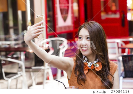オープンカフェでスマホを操作する女性 27084113