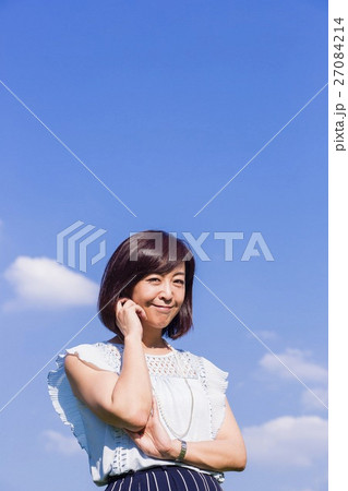 青空を背景に立つ女性 27084214