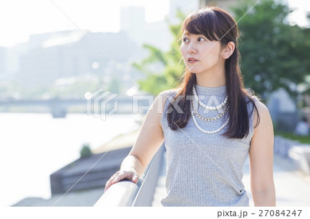 街中の川沿いに立つ女性 27084247