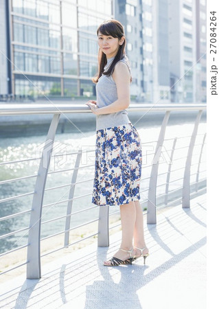 街中の川沿いに立つ女性 27084264