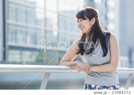 街中の川沿いに立つ女性 27084272