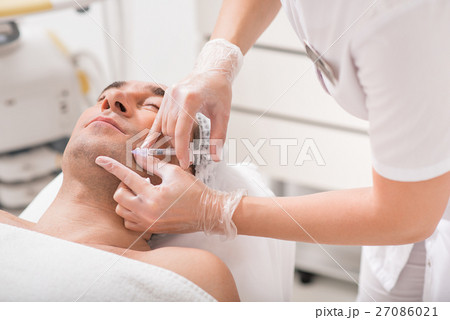 Skillful doctor injecting botox into human chin 27086021