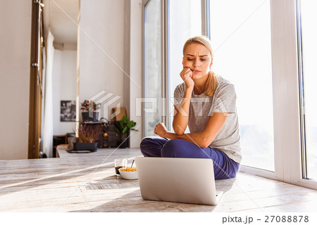 Blond girl using computer in her apartment 27088878