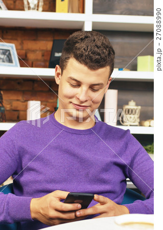 Young man holding a mobile phone and smiling 27088990