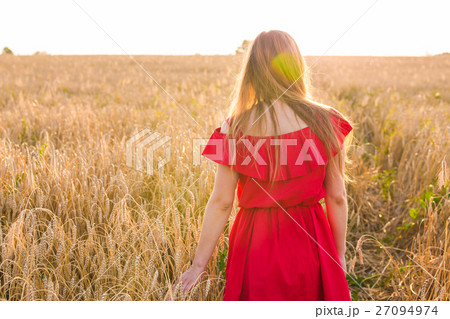 Girl in red dress on the field. Rear view Girl in red dress on the field. Rear view 27094974