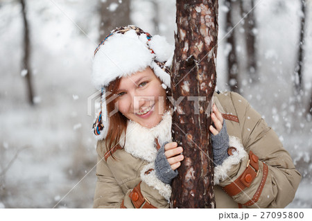 Happy smiling woman in coat with white fur, hat with ear flaps a 27095800