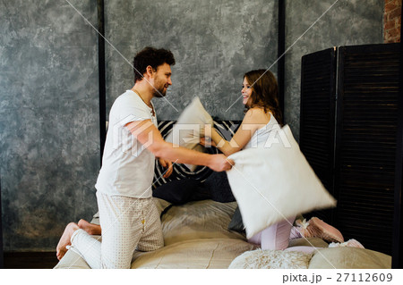 happy couple having pillow fight in bed at home 27112609