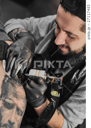 Tattoo master is tattooing in the tattoosalon 27117485