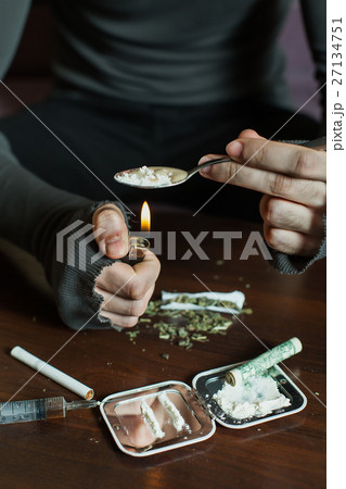 Addict in depression preparing dose of heroin. 27134751