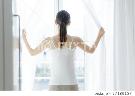 カーテンを開ける女性の写真素材