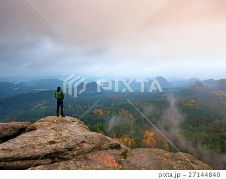 Hiker in windcheater, cap and trousers on rock Hiker in windcheater, cap and trousers on rock 27144840