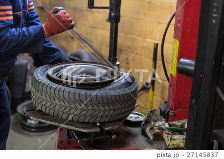 Professional auto mechanic replacing tire on wheel Professional auto mechanic replacing tire on wheel 27145837
