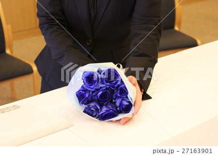 お別れに棺の上に青いバラの花束を手向ける女性の写真素材