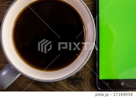 Smart phone with green screen next to coffee cup Smart phone with green screen next to coffee cup 27169058