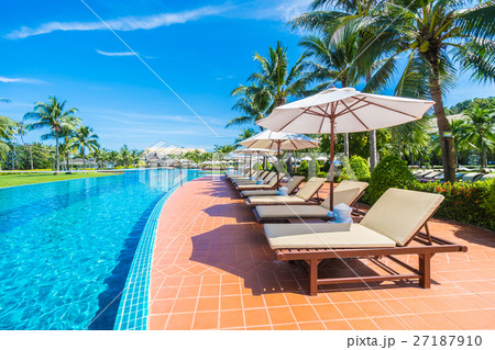Umbrella and chair around swimming pool 27187910