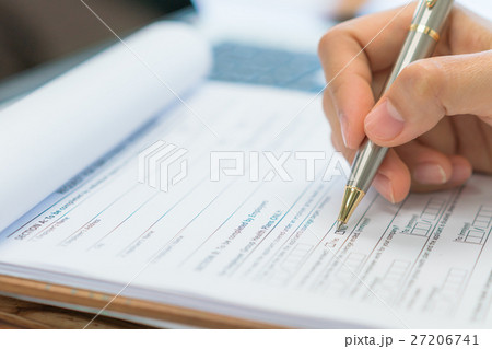 Hand with pen over application form . Hand with pen over application form . 27206741