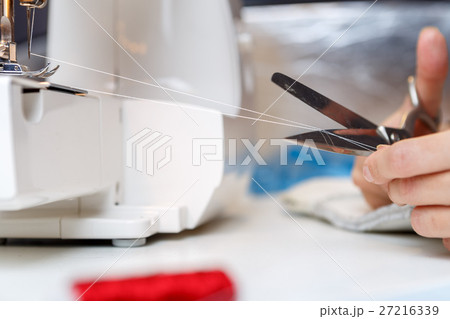 Seamstress shortens thread with scissors Seamstress shortens thread with scissors 27216339