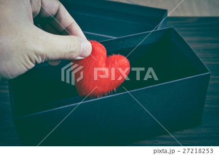Human hand put a red heart-shaped in gift box. 27218253