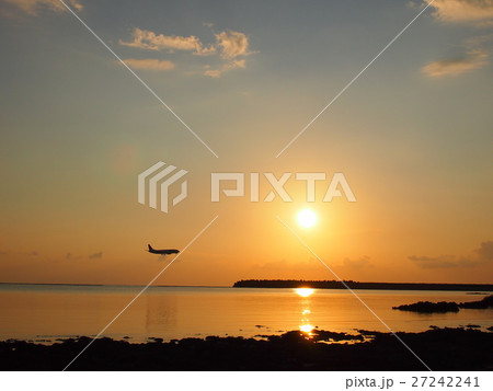 シンリ浜からの夕日と飛行機の写真素材