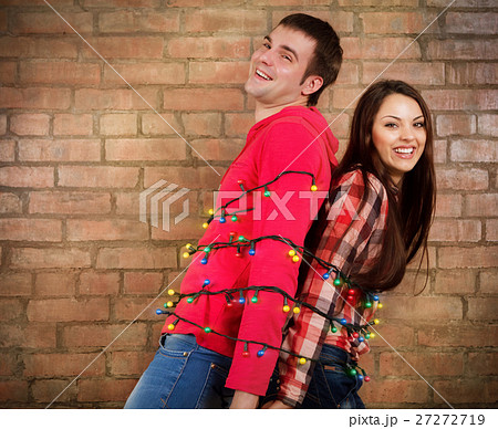 Happy young couple near brick wall with garland Happy young couple near brick wall with garland 27272719