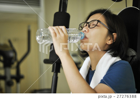 Asian woman drinking water after her workout. Asian woman drinking water after her workout. 27276388