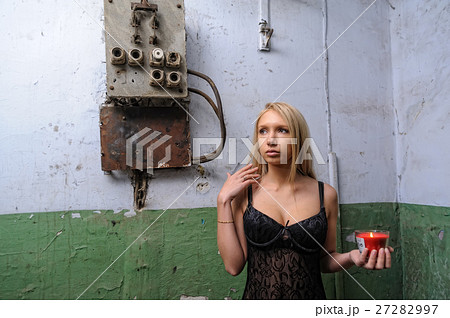 Woman left in a corridor with candle 27282997