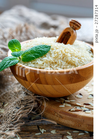 Grains of rice and a scoop in a wooden bowl. Grains of rice and a scoop in a wooden bowl. 27287314