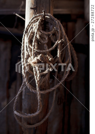 Twisted rope hanging on a wooden pole in the barn Twisted rope hanging on a wooden pole in the barn 27288722