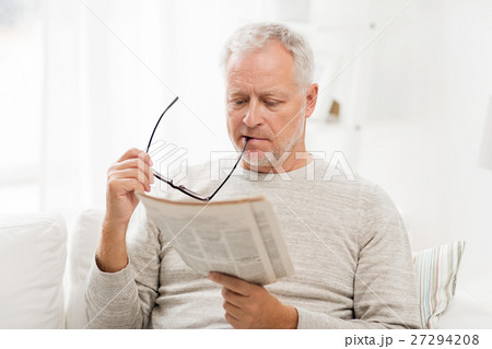 senior man in glasses reading newspaper at home 27294208