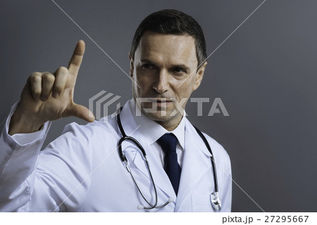 Handsome doctor gesturing on a grey background 27295667