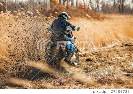 Enduro bike rider on a field with dry grass 27302785