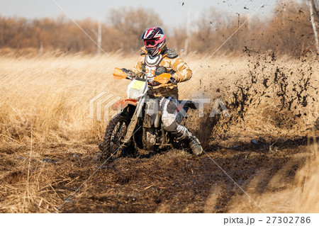 Enduro bike rider on a field with dry grass Enduro bike rider on a field with dry grass 27302786