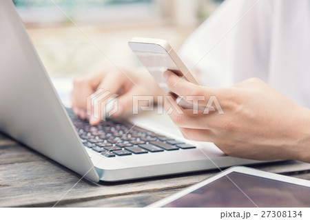 Female hands on laptop keyboard and smart phone 27308134