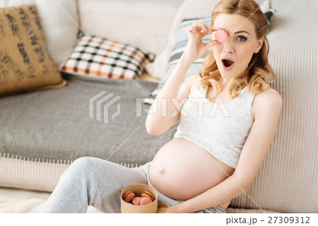 Pregnant joyful woman having fun with macaroons Pregnant joyful woman having fun with macaroons 27309312