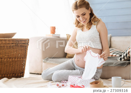 Pregnant woman looking at new baby clothes Pregnant woman looking at new baby clothes 27309316