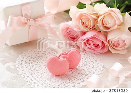 ピンクのハート型マカロンとピンクの薔薇のブーケとプレゼントの写真素材